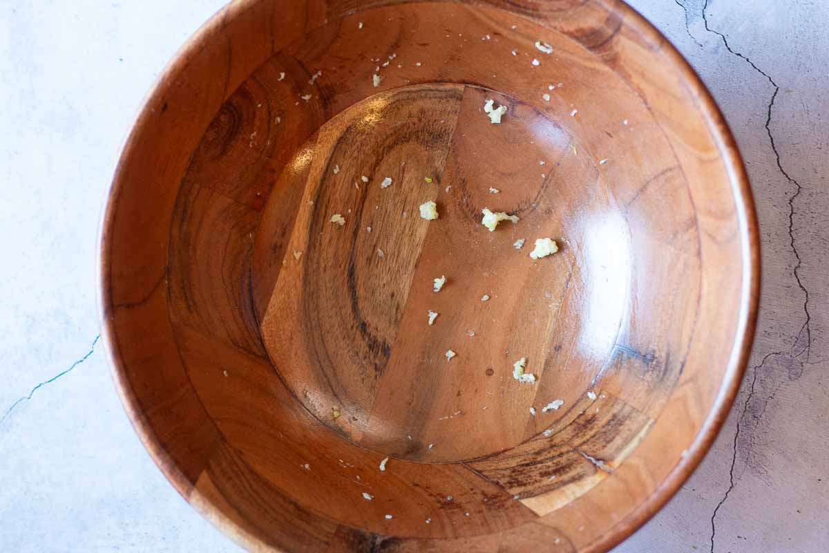 Rubbing garlic on the inside of a wooden salad bowl.