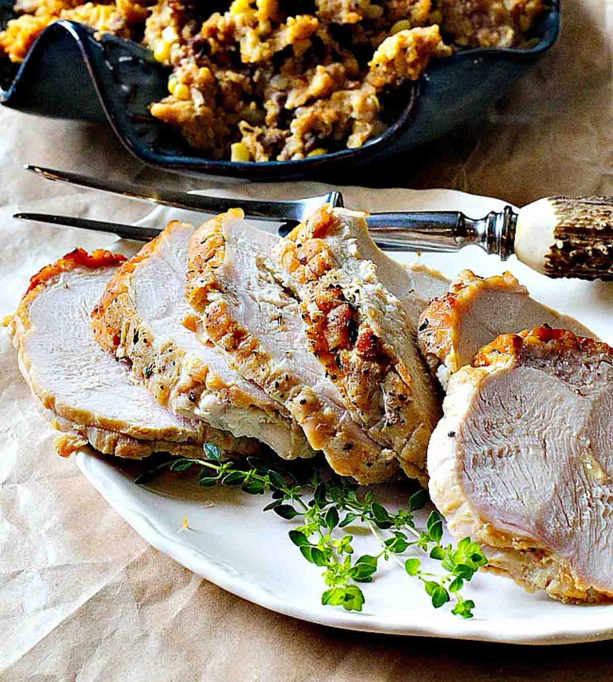 Sliced boneless turkey breast roast on a white platter.