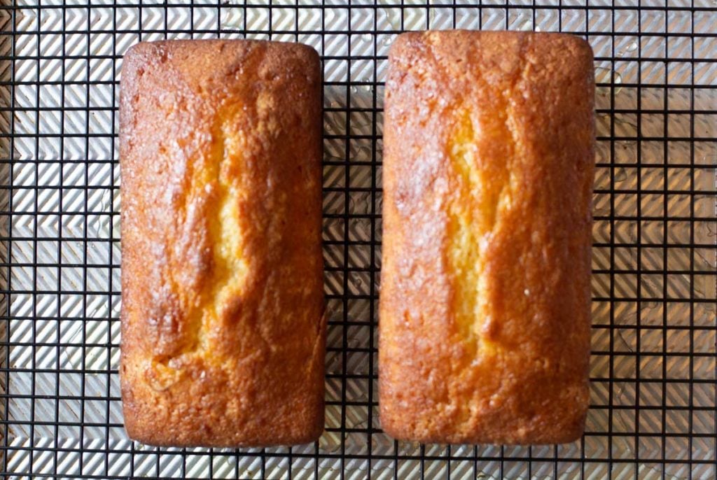 Two loaves of orange pound cake cooling on a wire rack