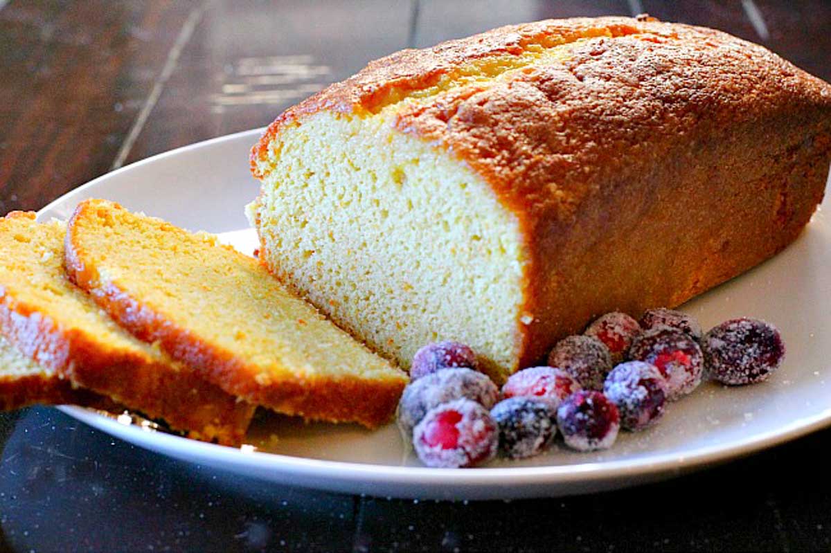 Sliced orange pound cake with sugared cranberries on the side