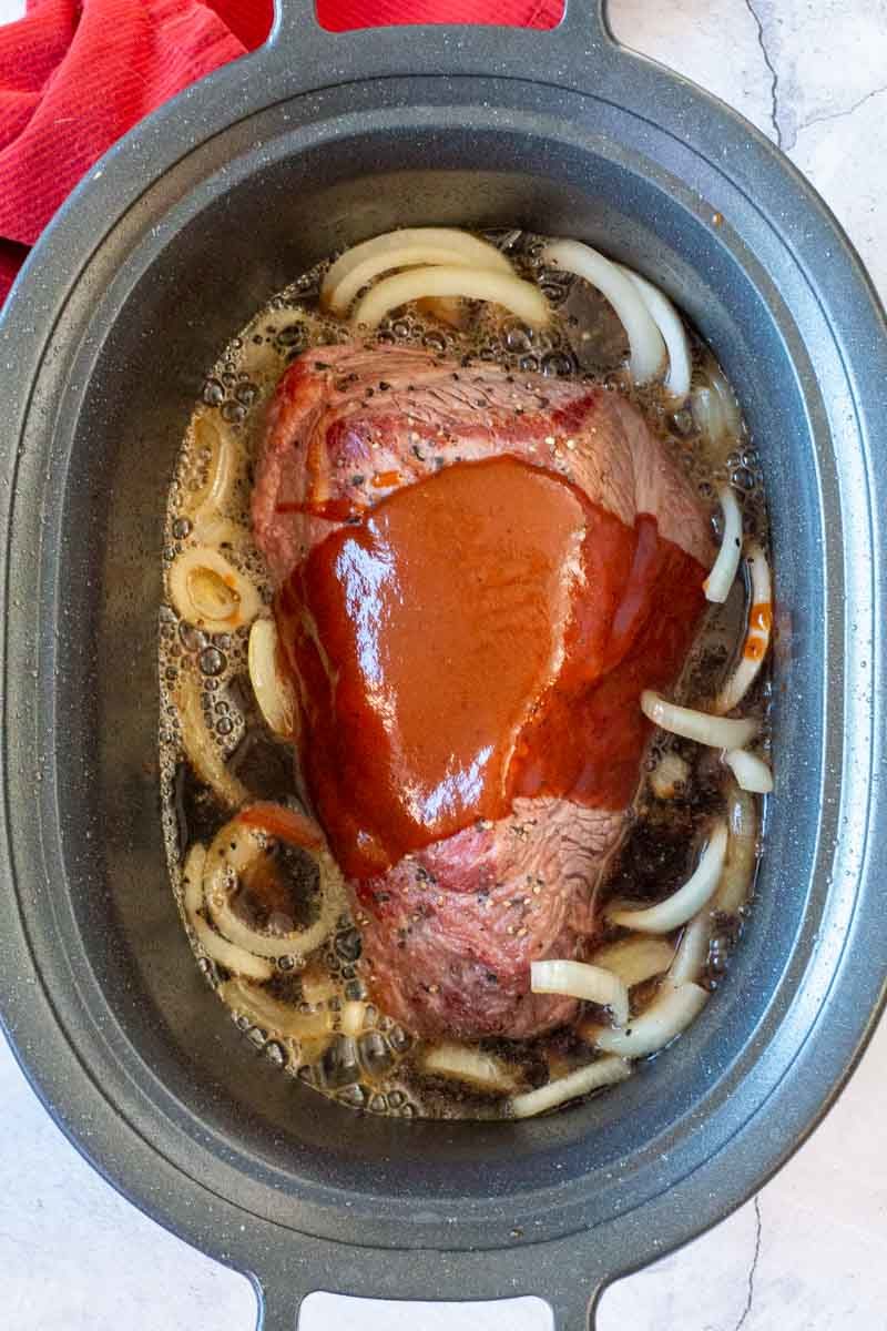 A beef brisket in the crockpot with coca cola and bbq sauce.