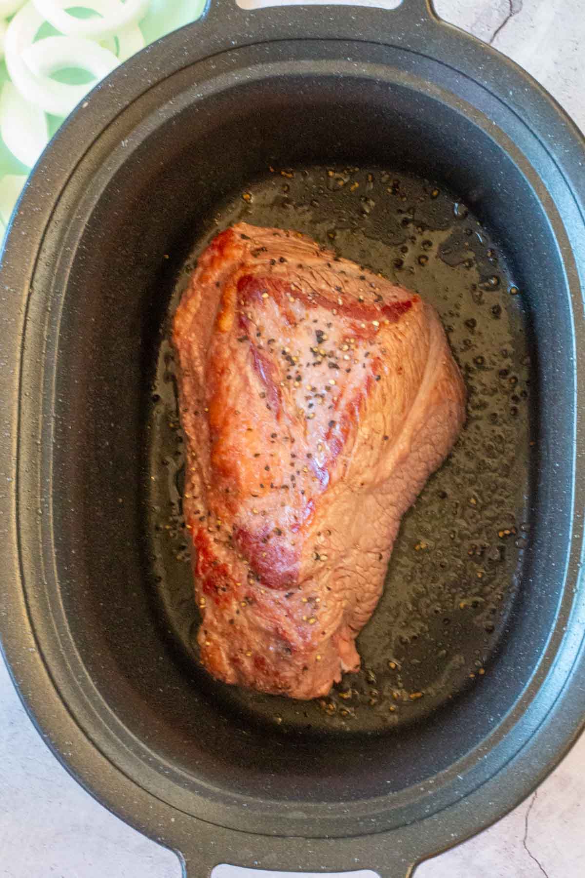 Searing a beef brisket to cook in a crockpot.