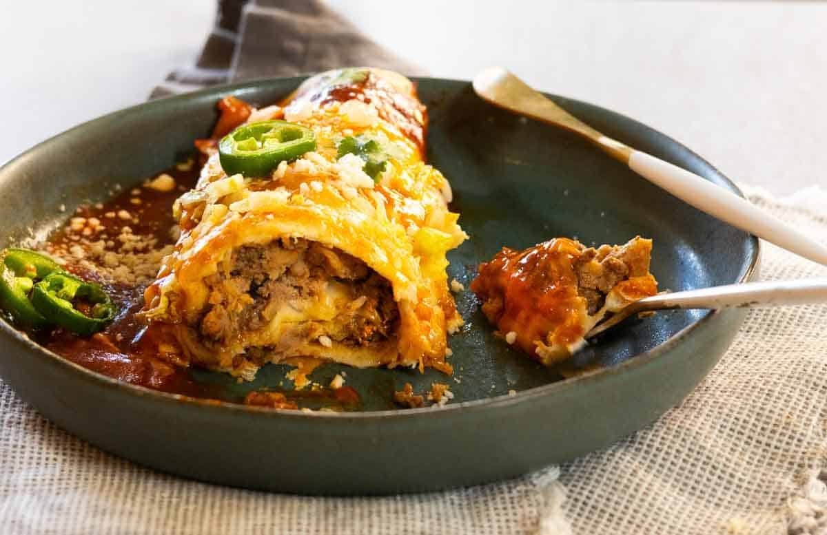 A enchilada style burrito on a plate.