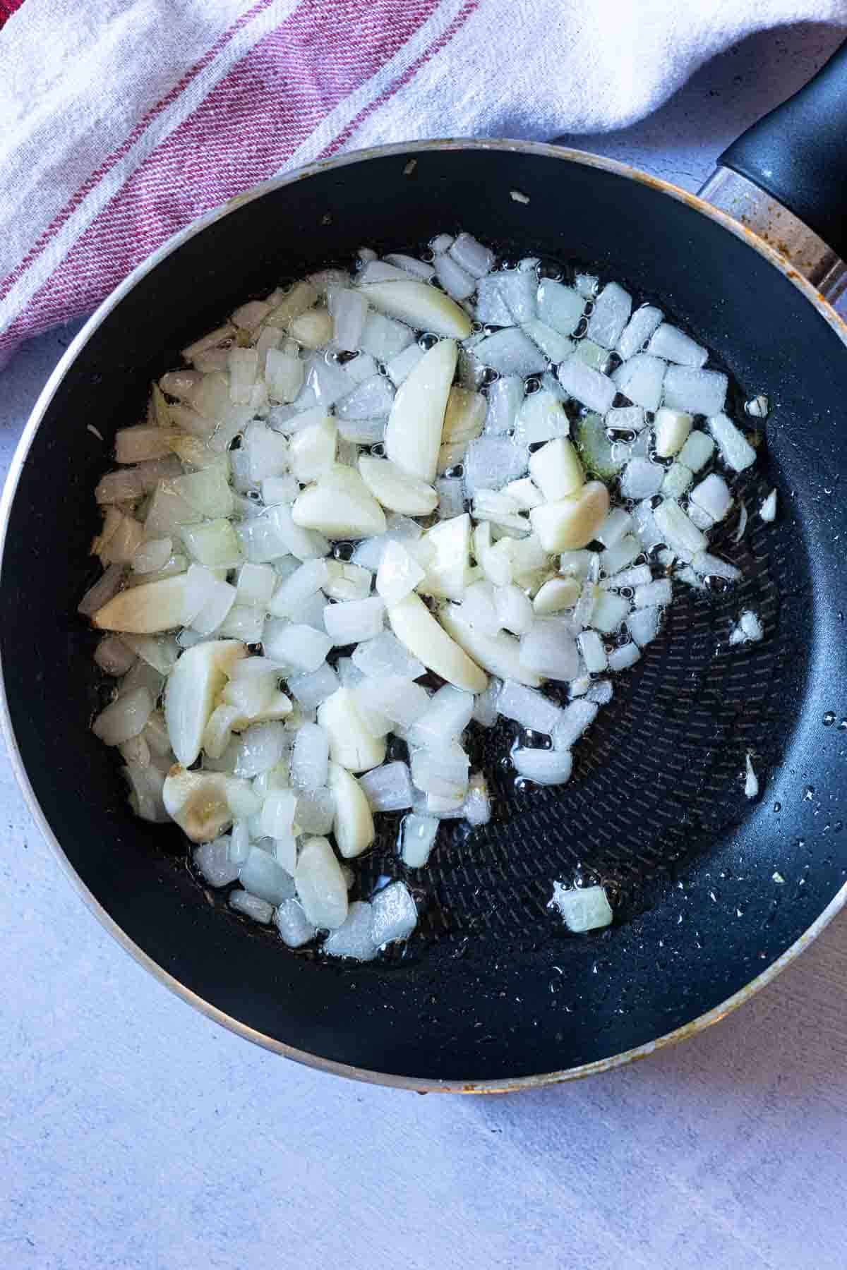 Cooking onions and garlic to season mayocoba bean soup.