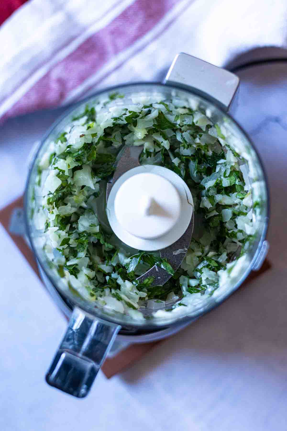 Using a small chopper machine to grind onions, garlic and parsley.