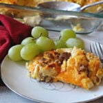 sausage egg cheese casserole on a vintage 1950's china plate with fresh green grapes