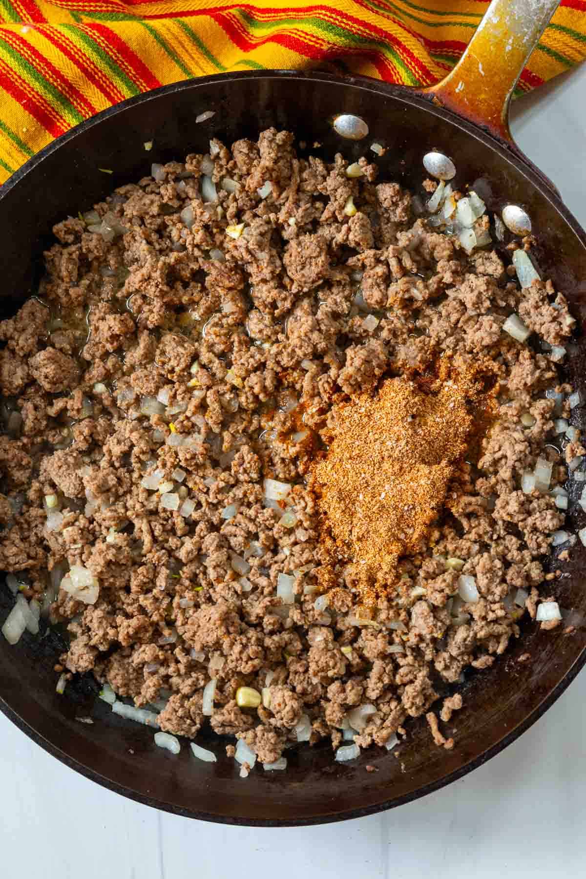Adding seasonings and taco seasoning to make filling for enchilada burritos.