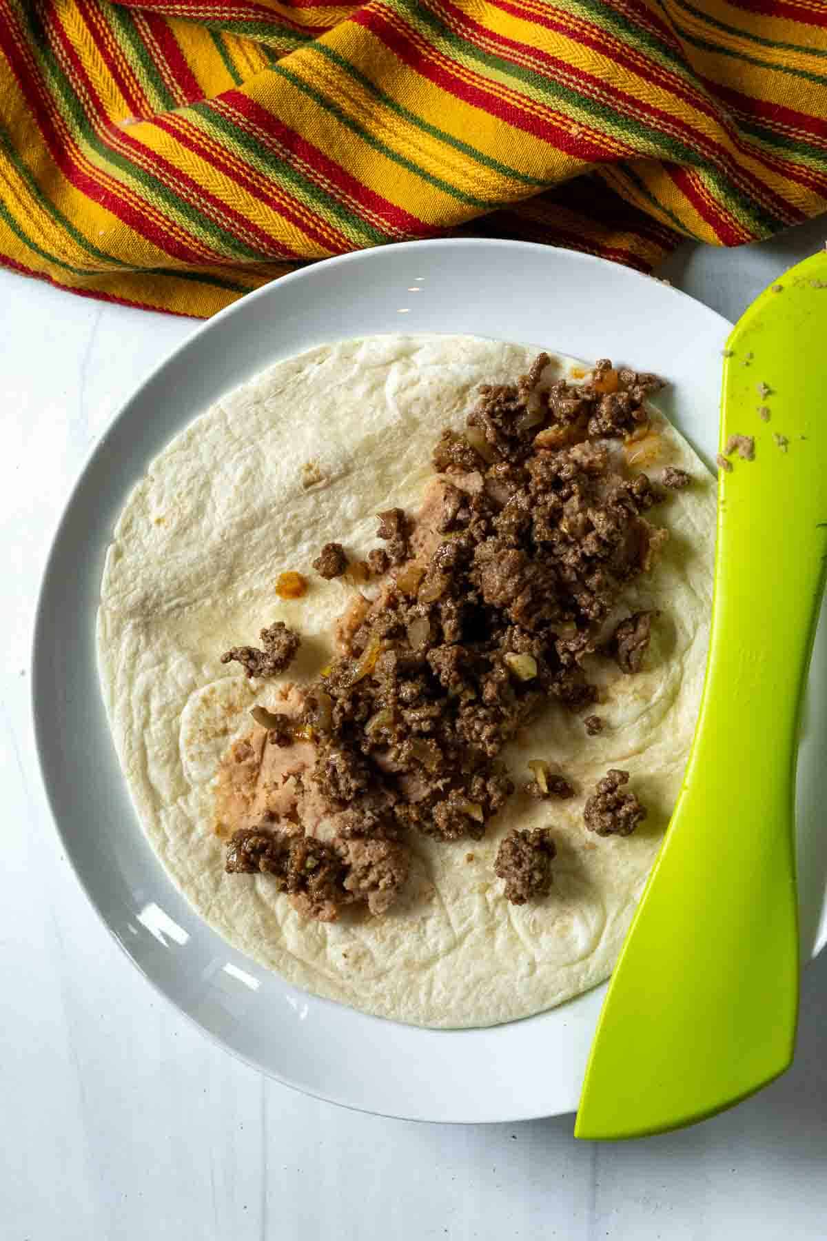 Adding ground beef mixture to make enchilada style burritos.