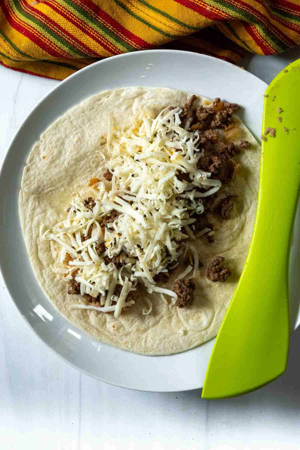 Adding cheese to burrito filling to make enchilada style burritos.
