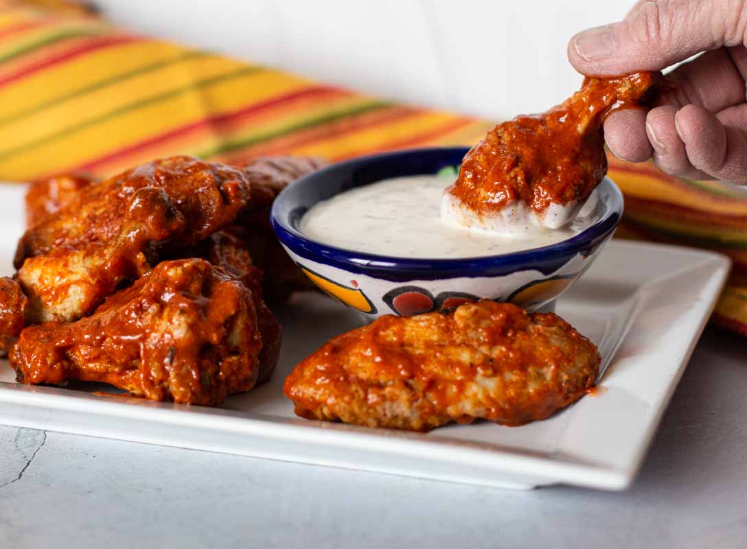 Dipping a baked chicken wing into ranch dressing.