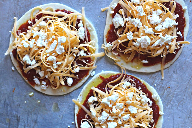 Tortilla pizza appetizer recipe using goat cheese on top of cheddar cheese