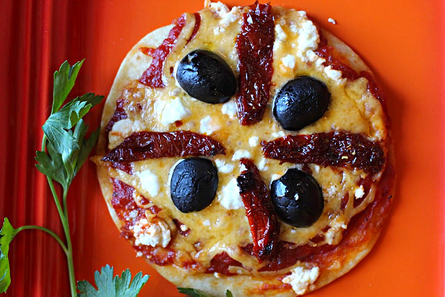 Tortilla pizza appetizer with cheddar cheese, goat cheese, sun dried tomatoes and black olives