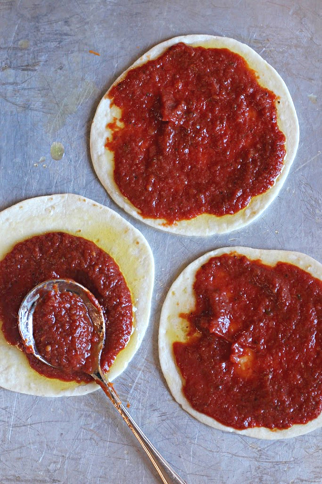 Adding sauce to tortilla pizza appetizers