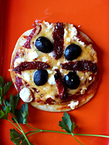 Tortilla pizza appetizer recipes. Flour tortilla topped with cheese, sun dried tomatoes, and olives.