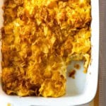 Cheesy potatoes with Corn Flakes in a white casserole dish.