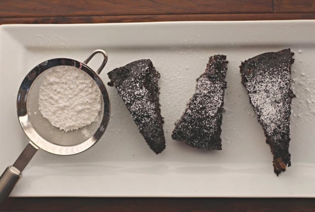 Chocolate banana bread recipe cut in wedges, sprinkled with powdered sugar on a rectangular white serving platter