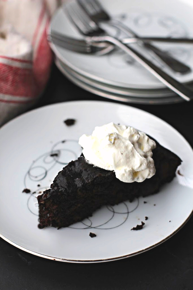Dark Chocolate banana bread recipe baked in a cast iron skillet and served on vintage china with a dollop of whipped cream