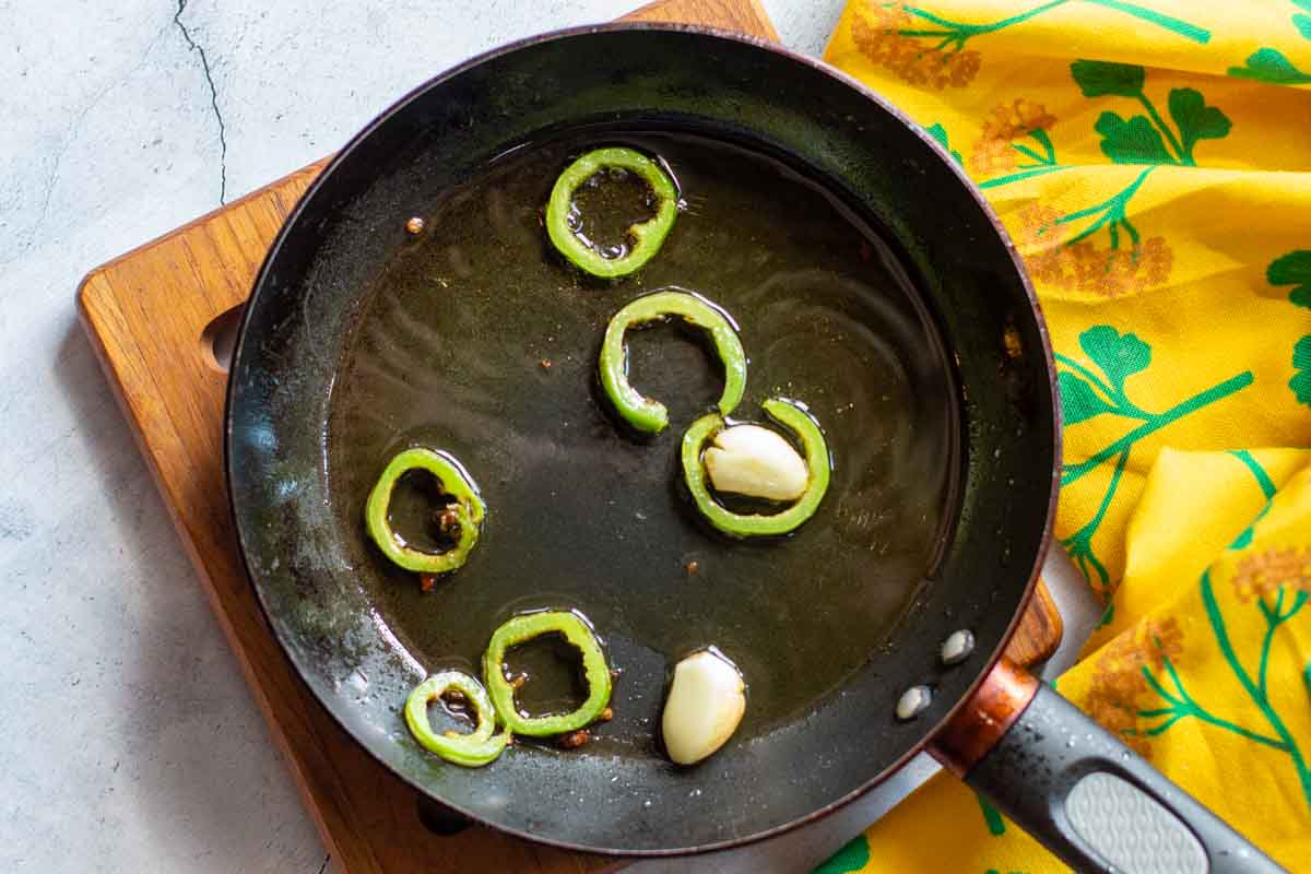 Cooking sliced jalapeno peppers and garlic cloves in olive oil.