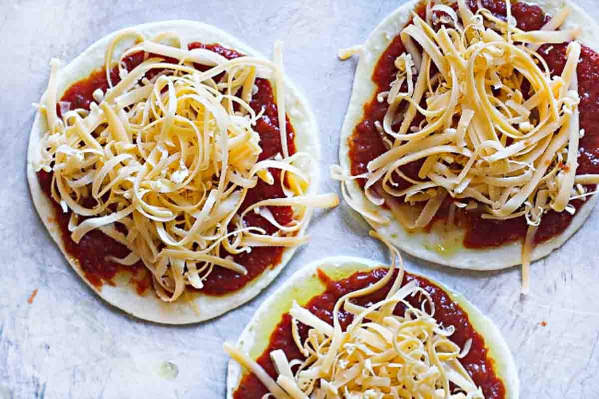 Step 3: Adding cheese to tortilla pizzas.
