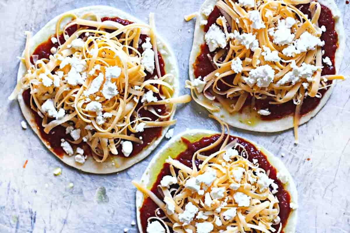 Adding goat cheese to flour tortilla pizza.