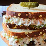 Homemade ham salad sandwich spread on oatnut bread topped with a pickle