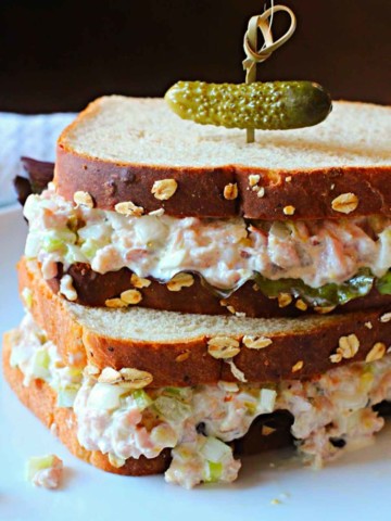 Homemade ham salad sandwich spread on oatnut bread topped with a pickle