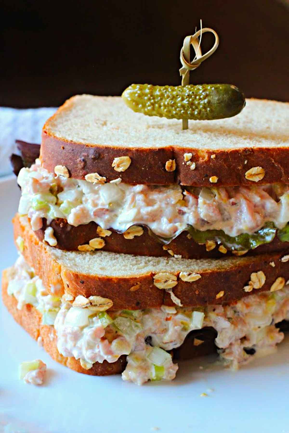 Homemade ham salad sandwich spread on oatnut bread topped with a pickle