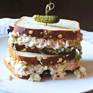 Ham salad sandwiches with lettuce topped with a pickle.