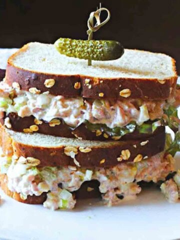 Ham salad sandwiches with lettuce topped with a pickle.
