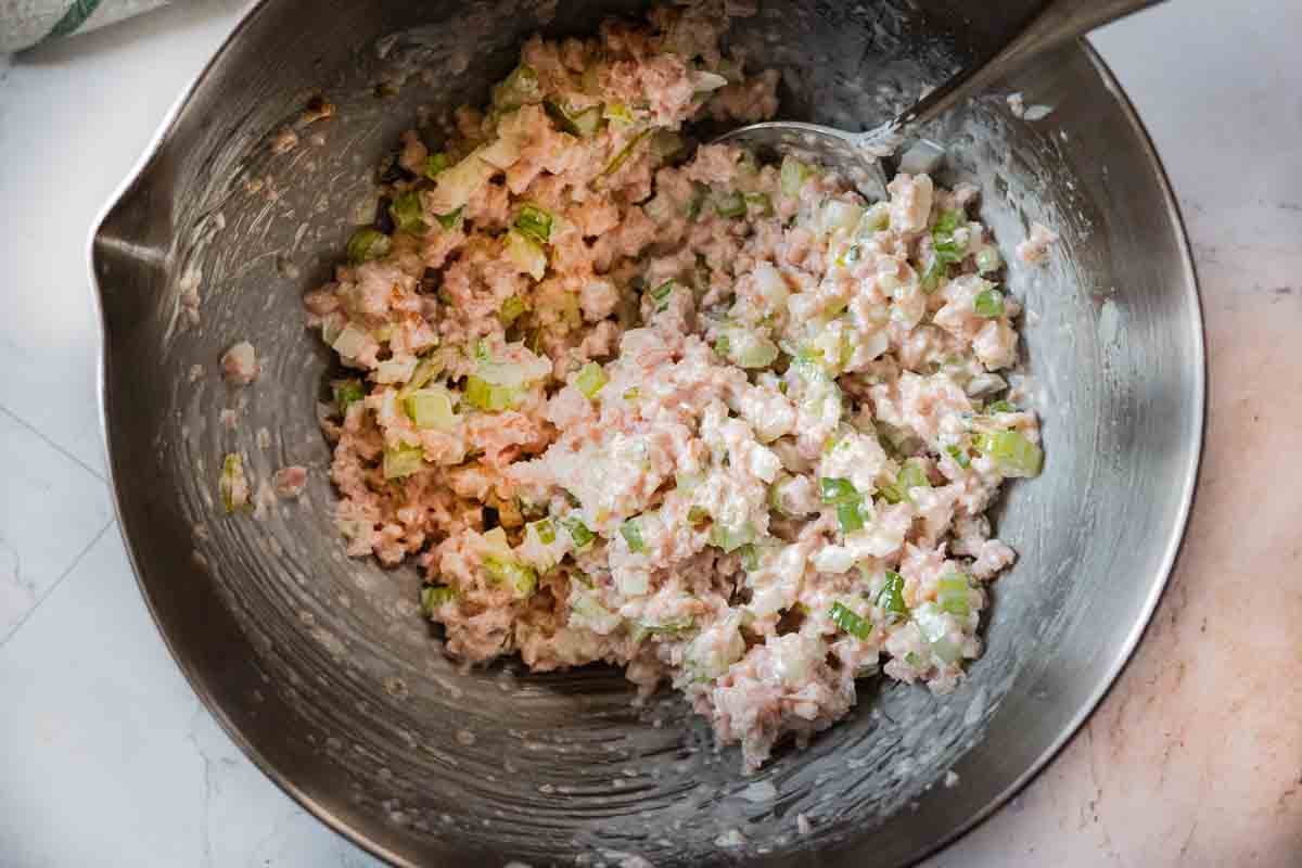 Mixing ingredients in a bowl to make ham salad.