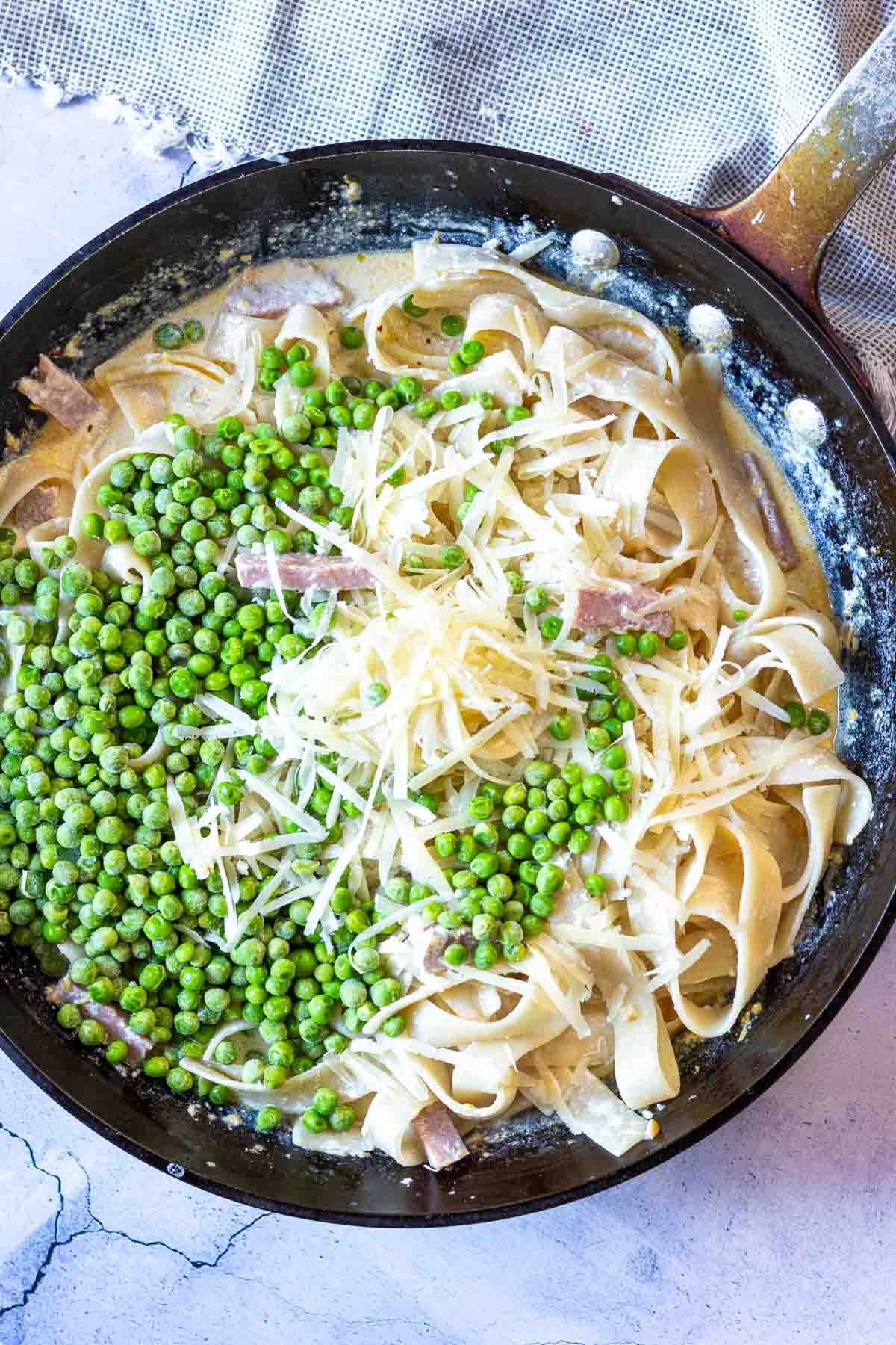 Adding peas and ham to pasta.