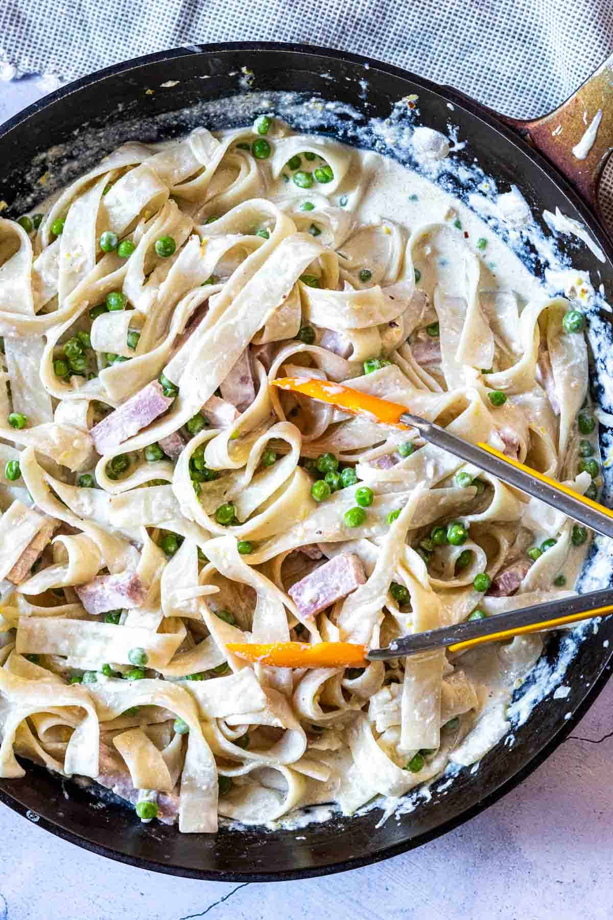 Mixing all ingredients together to make pasta with ham and peas.