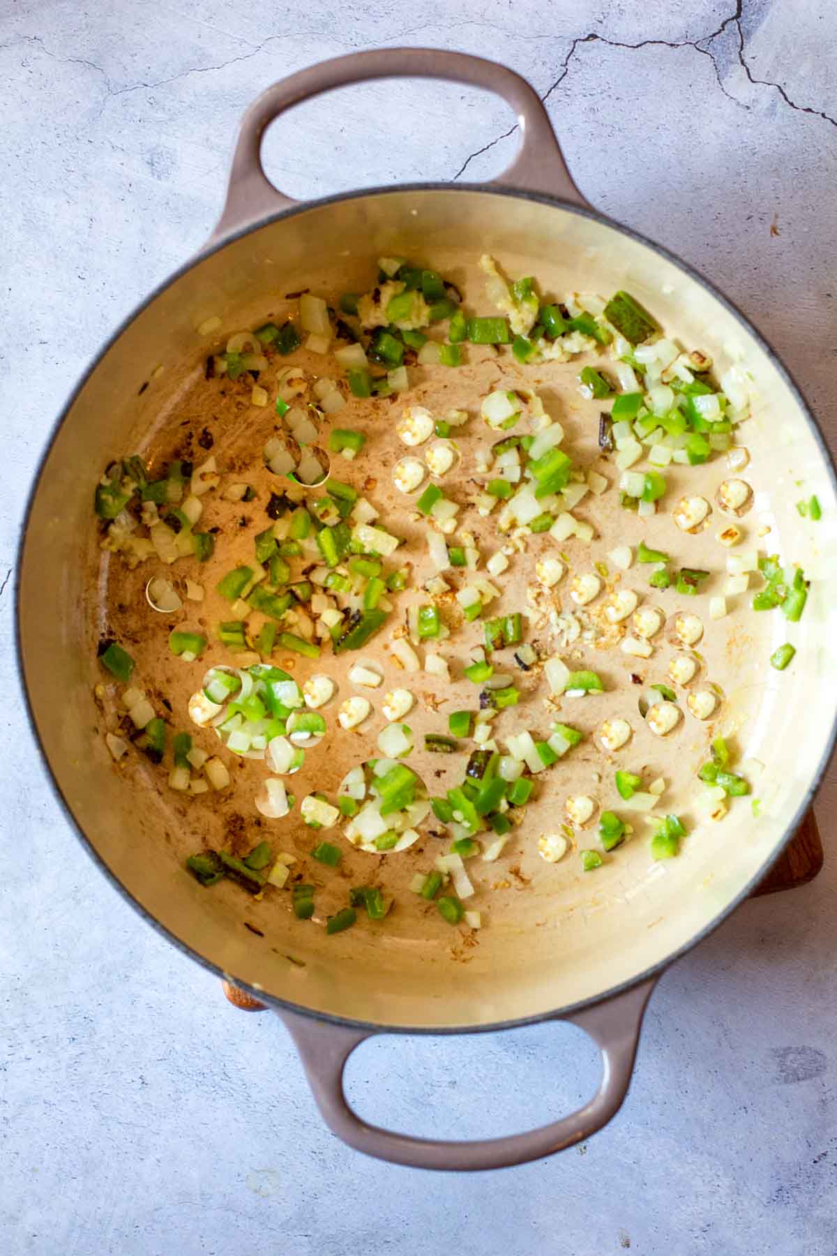 Cooking chopped onions and jalapeno peppers in a dutch oven.