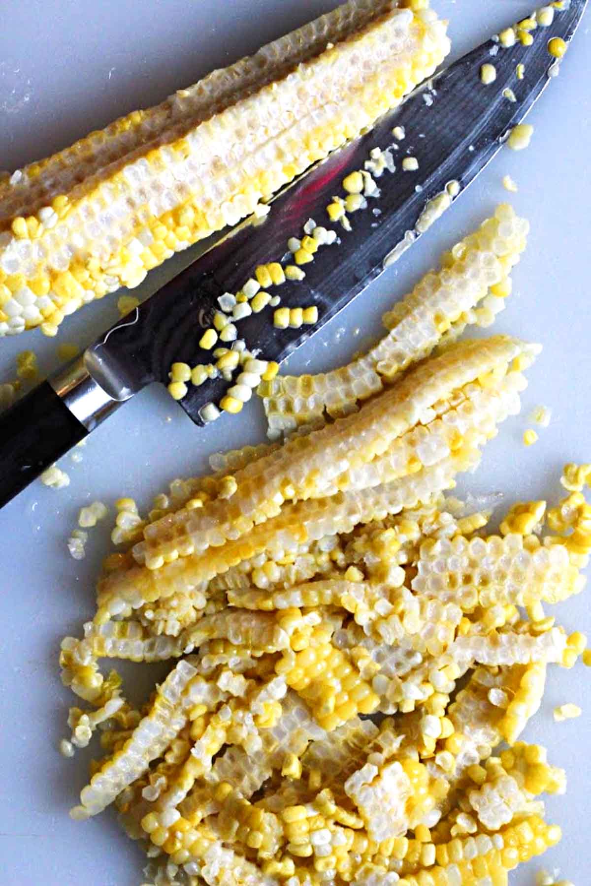 Removing corn kernels from cob using a knife.
