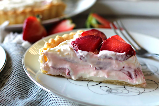 A slice of strawberry cream cheese tart topped with fresh sliced strawberries