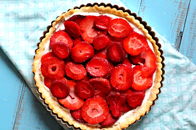 Sliced strawberries in a strawberry pie with cream cheese in a tart shell