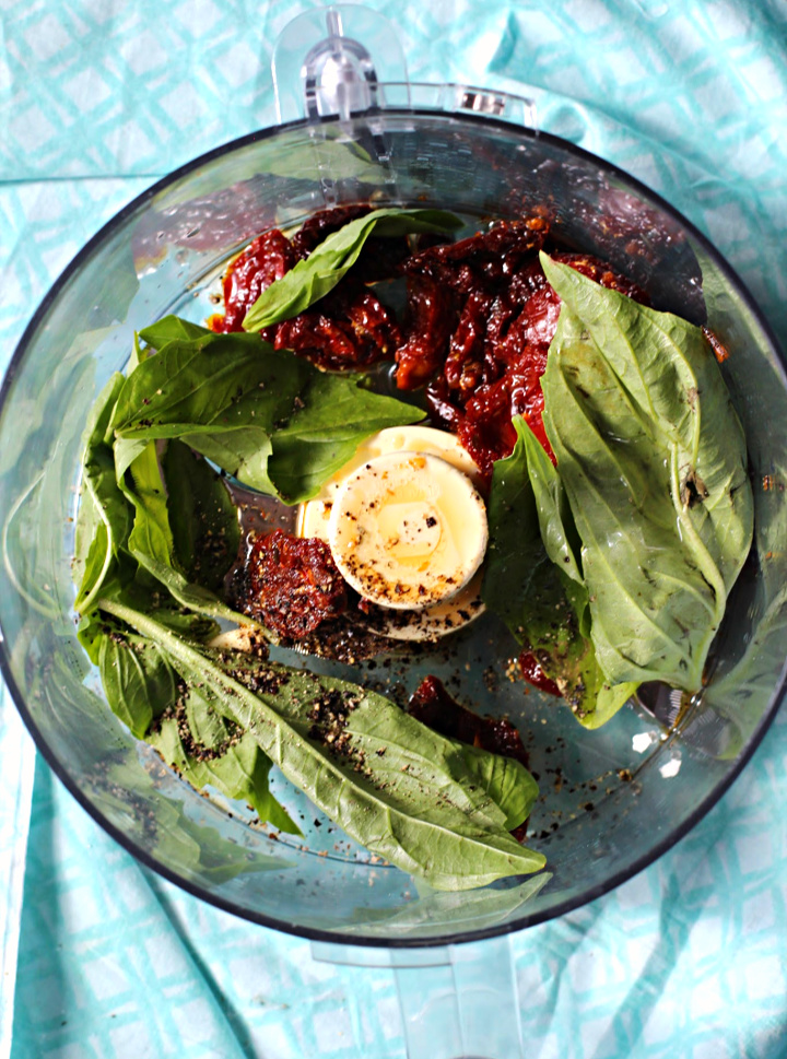 Basil leaves and sun dried tomatoes in a food processor