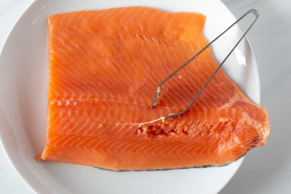 Using pin bone tweezers to remove pin bones from salmon