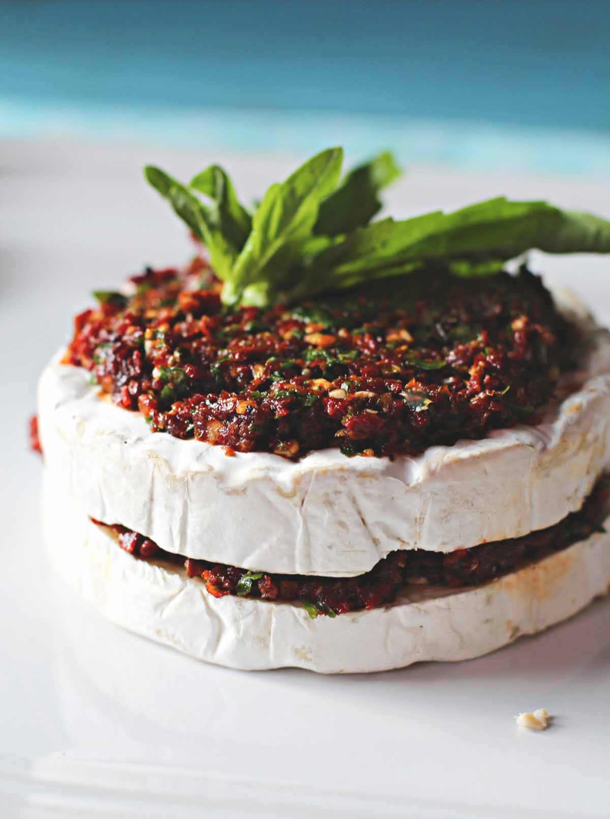 Brie appetizer stuffed with sundried tomatoes and topped with basil