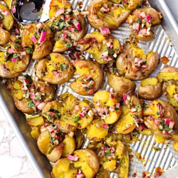 Smashed yukon gold potatoes with chimichurri sauce on a sheet pan