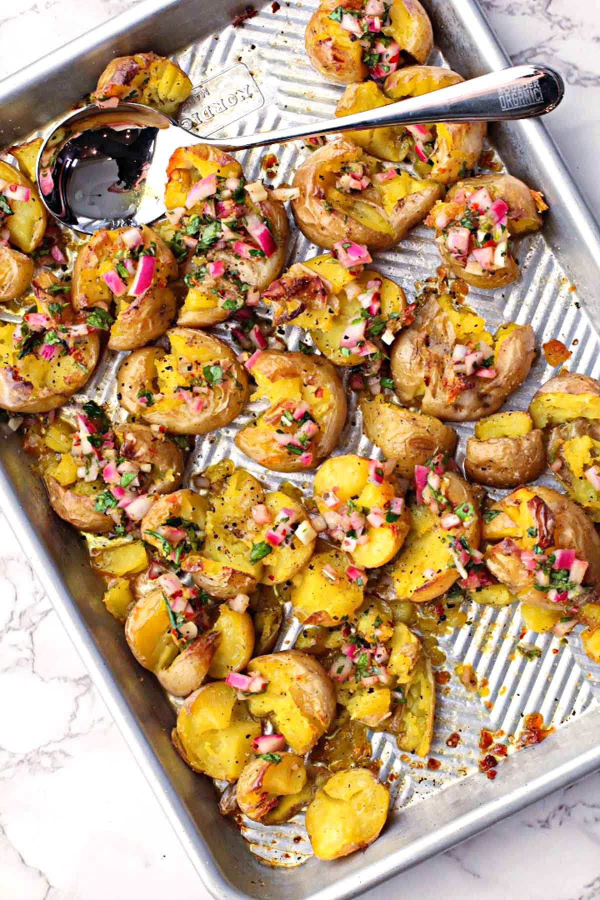 Smashed yukon gold potatoes with chimichurri sauce on a sheet pan