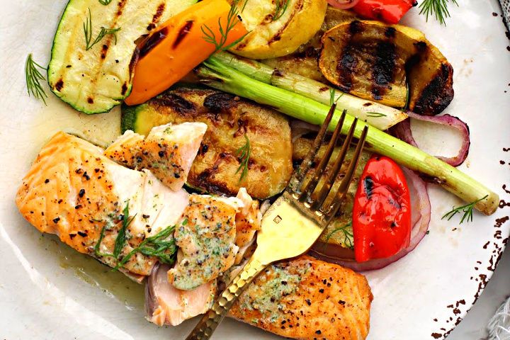 Easy grilled salmon fillets served with grilled vegetables on a rustic white plate