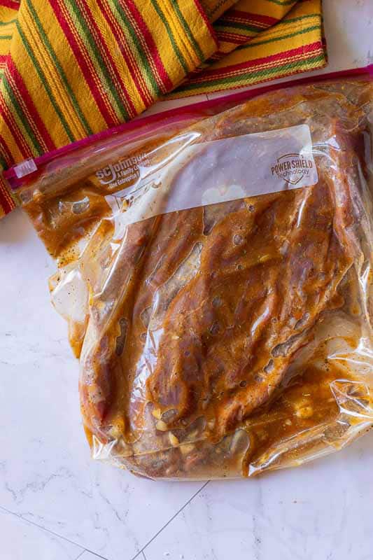 Placing flank steak and marinade ingredients in a plastic bag to marinate overnight.