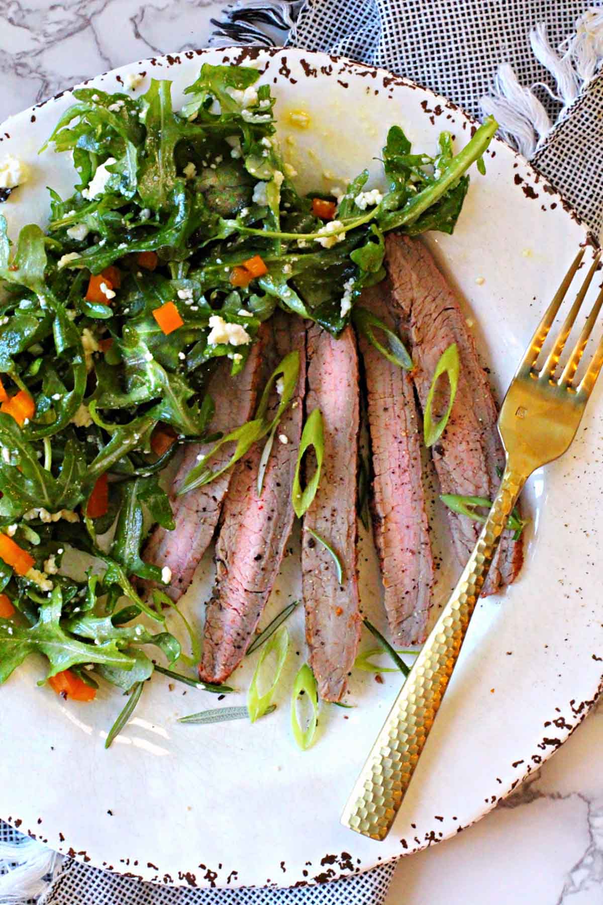 Sliced grilled flank steak served with a kale salad