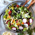 Southwestern Salad Recipe with corn and black beans served in a glass serving bowl with a side of cumin lime honey vinaigrette and cotija cheese
