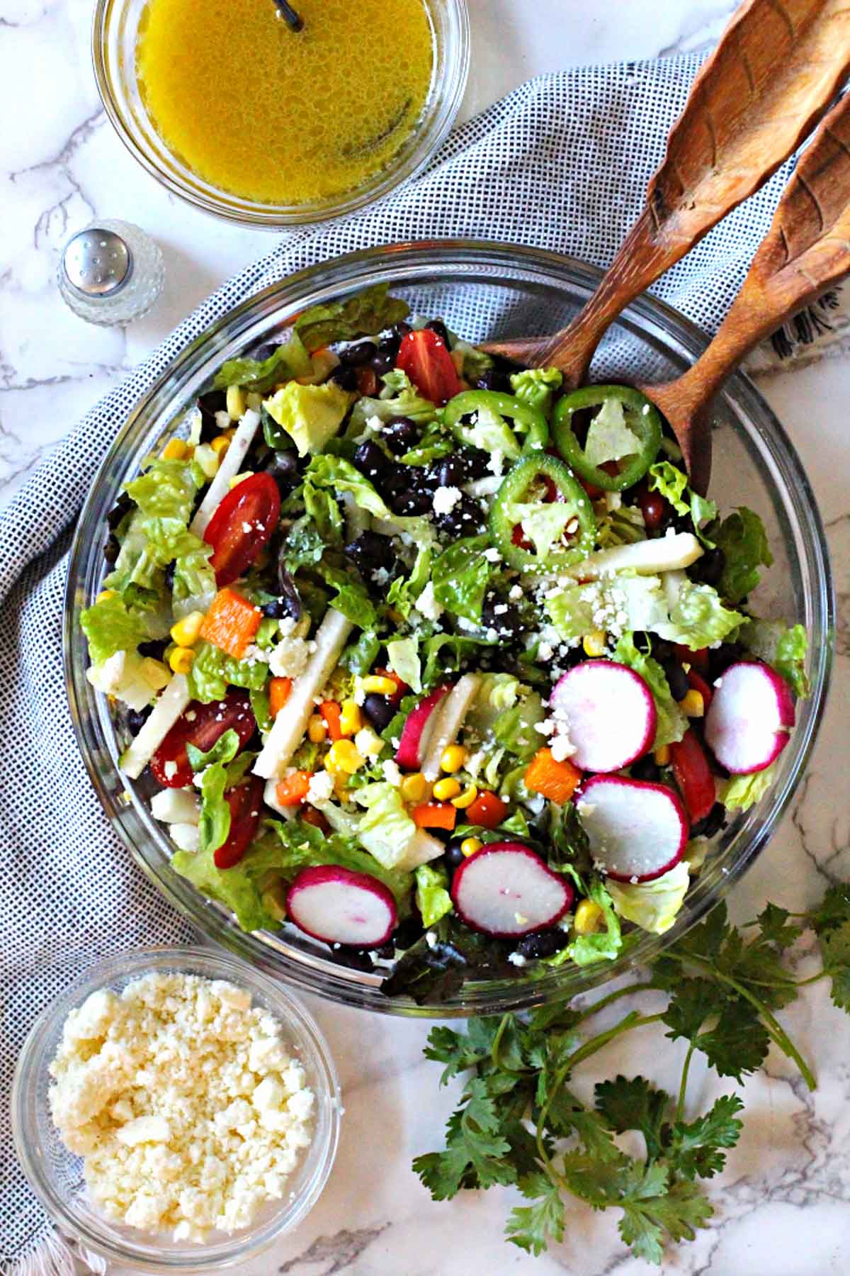 Southwestern Salad Recipe with corn and black beans served in a glass serving bowl with a side of cumin lime honey vinaigrette and cotija cheese