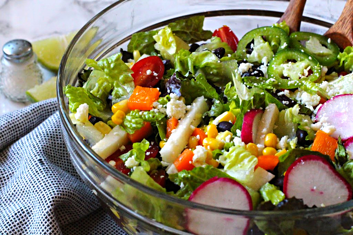 Southwestern Salad Recipe with Black Beans, corn, radishes, jicama, tomatoes served in a glass salad bowl.