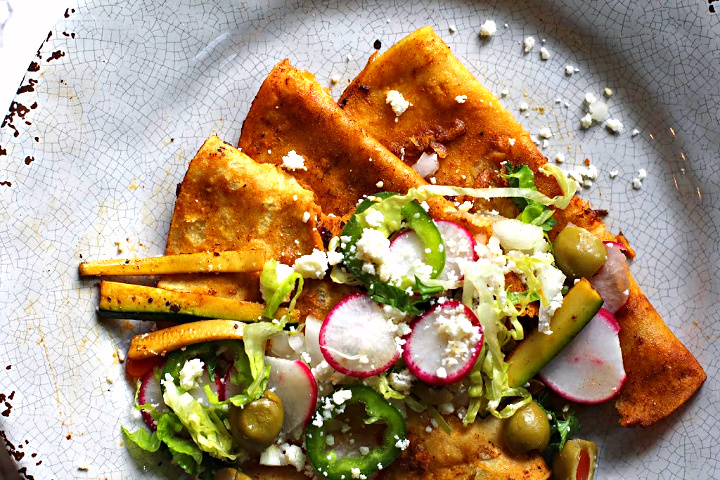 Red chile enchiladas topped with strips of zucchini, radish, sliced jalapenos, green olives, sliced romaine lettuce.