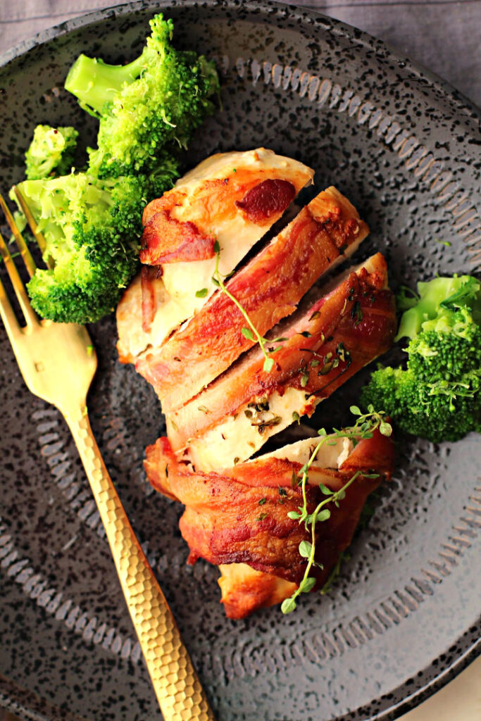 Chicken and bacon with thyme. Chicken wrapped in bacon with sprigs of fresh thyme served with fresh broccoli.