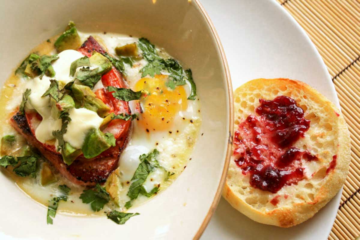 Baked Eggs with Ham and Avocado served with an English muffin.